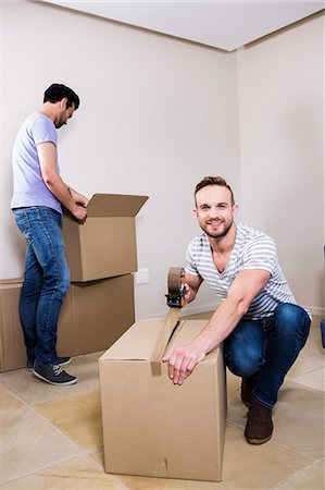 person taping a box - Gay couple moving into new home Stock Photo - Premium Royalty-Free, Code: 6109-08390521