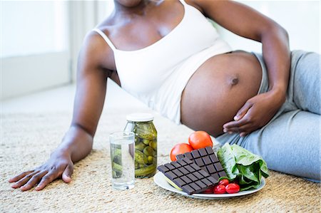 pregnant black woman belly - Woman lying down to enjoy some snacks Stock Photo - Premium Royalty-Free, Code: 6109-08395184