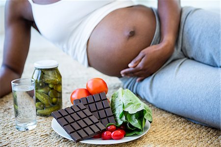 pregnant black woman belly - Woman lying down to enjoy some snacks Stock Photo - Premium Royalty-Free, Code: 6109-08395185