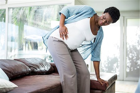 simsearch:6109-06004883,k - Pregnant woman struggling to get up from the couch Foto de stock - Sin royalties Premium, Código: 6109-08395221