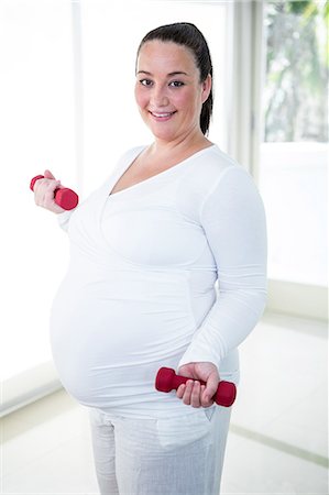 simsearch:6109-08395398,k - Pregnant smiling woman lifting dumbbell Photographie de stock - Premium Libres de Droits, Code: 6109-08395405