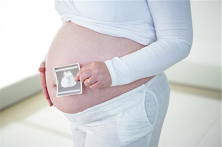 simsearch:6109-08395398,k - Pregnant woman holding sonogram near her belly Photographie de stock - Premium Libres de Droits, Code: 6109-08395415