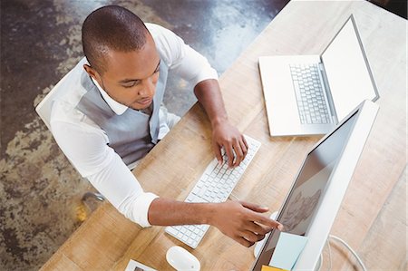 editor (male) - High angle view of businessman pointing at computer Stock Photo - Premium Royalty-Free, Code: 6109-08395596