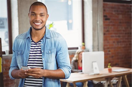 Portrait of smiling man using phone at office Photographie de stock - Premium Libres de Droits, Code: 6109-08395680