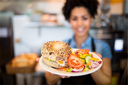 simsearch:6109-08395937,k - Pretty waitress serving lunch to camera Stock Photo - Premium Royalty-Free, Code: 6109-08395934