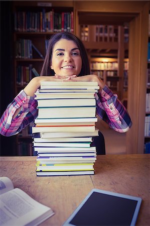 simsearch:6109-08396221,k - Cheerful female student leaning on book stack Fotografie stock - Premium Royalty-Free, Codice: 6109-08396260