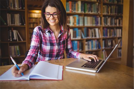 student on laptop - Happy female student with laptop writing on book Foto de stock - Sin royalties Premium, Código: 6109-08396220