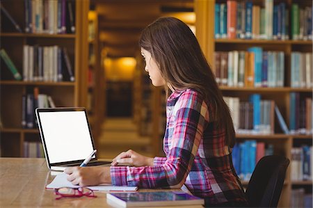 Female student using laptop while writing on book Foto de stock - Sin royalties Premium, Código: 6109-08396227