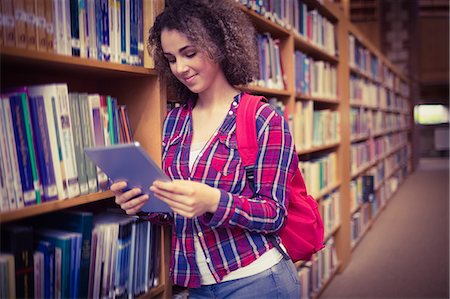 simsearch:6109-08396555,k - Pretty student in the library using tablet Photographie de stock - Premium Libres de Droits, Code: 6109-08396551