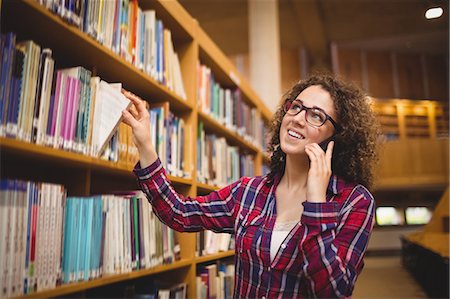 simsearch:6102-07843687,k - Pretty student in the library taking book Stock Photo - Premium Royalty-Free, Code: 6109-08396566