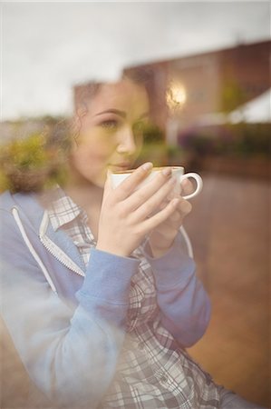 simsearch:6109-08395941,k - Pretty student sitting by the window having coffee Photographie de stock - Premium Libres de Droits, Code: 6109-08396526