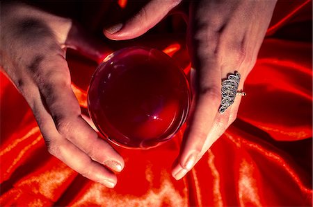 Overhead view of cropped hands using red crystal ball Photographie de stock - Premium Libres de Droits, Code: 6109-08396678