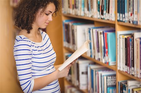 simsearch:400-08650429,k - Pretty student in library reading book Foto de stock - Royalty Free Premium, Número: 6109-08396602