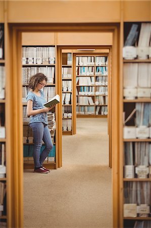 simsearch:400-08650429,k - Pretty student in library reading book Foto de stock - Royalty Free Premium, Número: 6109-08396630