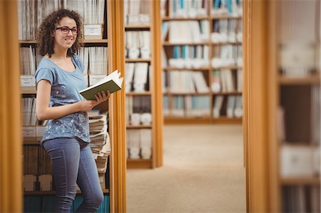 Pretty student in library reading book Stock Photo - Premium Royalty-Free, Code: 6109-08396631