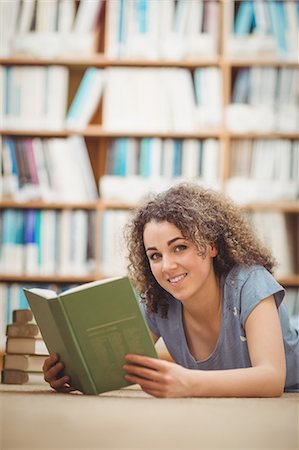 Pretty student in library reading book Photographie de stock - Premium Libres de Droits, Code: 6109-08396637