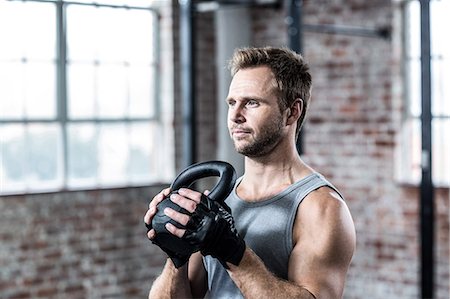 simsearch:6109-08397960,k - Fit focused man lifting a kettlebell Stock Photo - Premium Royalty-Free, Code: 6109-08396764