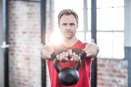 Muscular focused man lifting kettlebells Stock Photo - Premium Royalty-Free, Code: 6109-08396797