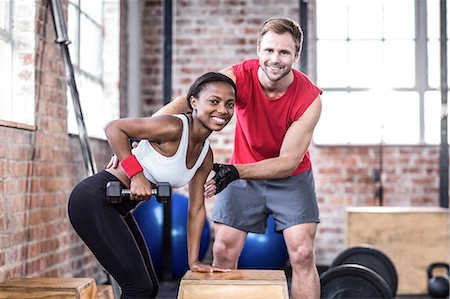 pictures of women standing on men - Muscular woman lifting dumbbell with her trainer Stock Photo - Premium Royalty-Free, Code: 6109-08396864