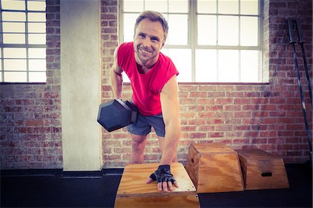 simsearch:6109-08397101,k - Muscular man lifting dumbbell lean on a box Stock Photo - Premium Royalty-Free, Code: 6109-08396870