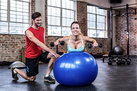 Personal trainer with client lifting dumbbells on exercise ball Stock Photo - Premium Royalty-Free, Code: 6109-08397160