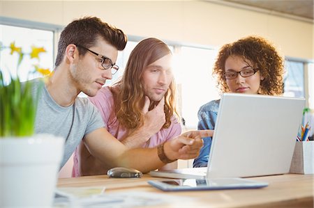 simsearch:6109-08397384,k - Businessman pointing at laptop while explaining colleagues Foto de stock - Sin royalties Premium, Código: 6109-08397338