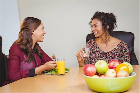 simsearch:6109-08397541,k - Businesswomen smiling while having breakfast Stock Photo - Premium Royalty-Free, Code: 6109-08397538