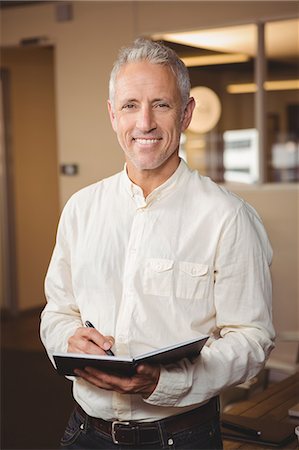 Happy creative businessman holding book in office Photographie de stock - Premium Libres de Droits, Code: 6109-08397645