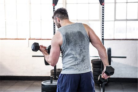 sweaty tank top - Fit man lifting heavy black dumbbells Stock Photo - Premium Royalty-Free, Code: 6109-08397769