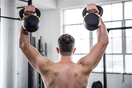 simsearch:6109-08397966,k - Fit shirtless man working out with kettlebells Photographie de stock - Premium Libres de Droits, Code: 6109-08397823