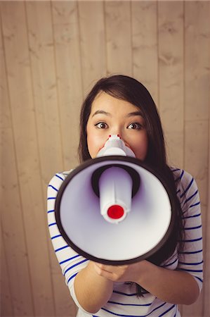 Beautiful woman shouting with megaphone Stock Photo - Premium Royalty-Free, Code: 6109-08398349