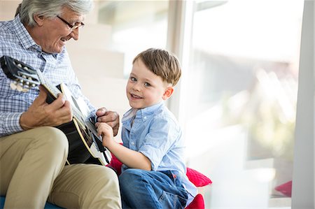 senior man playing guitar with child - Grandfather teaching grandson to play guitar Stock Photo - Premium Royalty-Free, Code: 6109-08398844