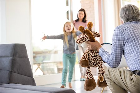 family in living room - Grandfather offering a toy to granddaughter Stock Photo - Premium Royalty-Free, Code: 6109-08398831