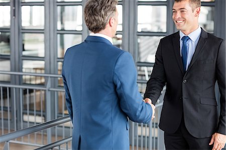 simsearch:6109-08690271,k - Two smiling businessmen shaking hands Fotografie stock - Premium Royalty-Free, Codice: 6109-08399192