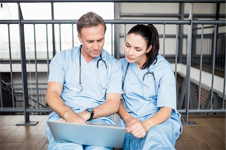 Doctors using laptop while sitting on floor Stock Photo - Premium Royalty-Free, Code: 6109-08399335