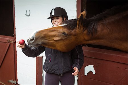 simsearch:6109-08399507,k - Pretty woman giving apple to horse Foto de stock - Sin royalties Premium, Código: 6109-08399494
