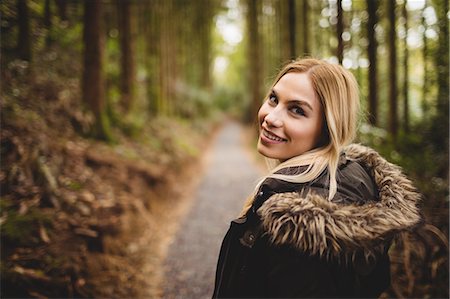 Beautiful blonde woman walking on road surrounded by forest Stock Photo - Premium Royalty-Free, Code: 6109-08481683
