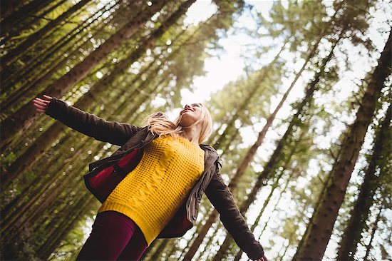 Beautiful blonde woman with arms outstretched in the woods Stock Photo - Premium Royalty-Free, Image code: 6109-08481685