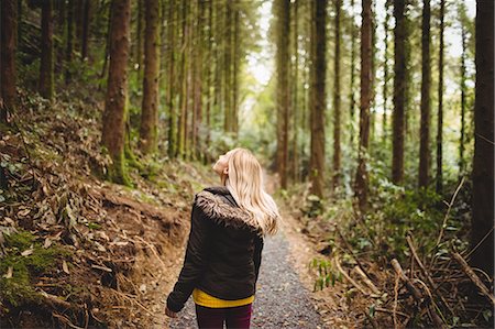 Beautiful blonde woman walking on road surrounded by forest Photographie de stock - Premium Libres de Droits, Code: 6109-08481686