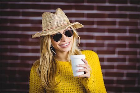 simsearch:6109-08398200,k - Beautiful blonde hipster holding takeaway cup on brick wall Stock Photo - Premium Royalty-Free, Code: 6109-08481703