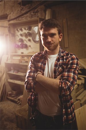 Carpenter smiling at the camera in a dusty workshop Photographie de stock - Premium Libres de Droits, Code: 6109-08481898