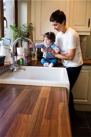 simsearch:6109-08488688,k - Cute mother holding her baby in the kitchen Stock Photo - Premium Royalty-Free, Code: 6109-08481800