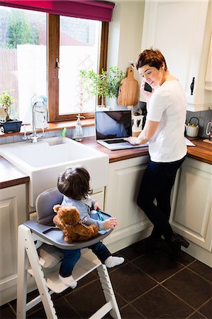 Woman using laptop while baby sitting on a baby chair in the kitchen Photographie de stock - Premium Libres de Droits, Code: 6109-08481808