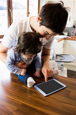 embrace kitchen - Cute mother showing tablet to her baby in the kitchen Stock Photo - Premium Royalty-Free, Code: 6109-08481809