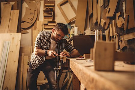 simsearch:6109-08481913,k - Carpenter working on his craft in a dusty workshop Foto de stock - Sin royalties Premium, Código: 6109-08481961