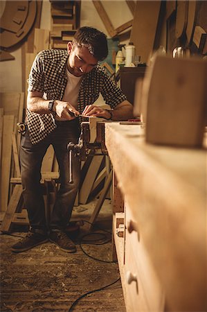 simsearch:6109-08481817,k - Carpenter working on his craft in a dusty workshop Foto de stock - Sin royalties Premium, Código: 6109-08481962