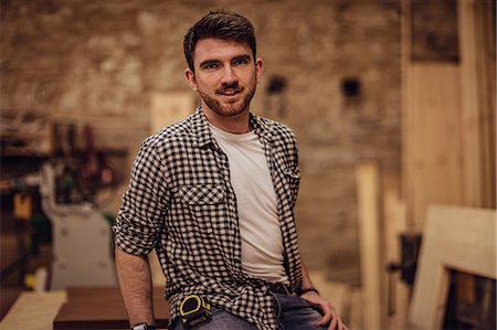 Carpenter smiling at the camera in a dusty workshop Photographie de stock - Premium Libres de Droits, Code: 6109-08481997