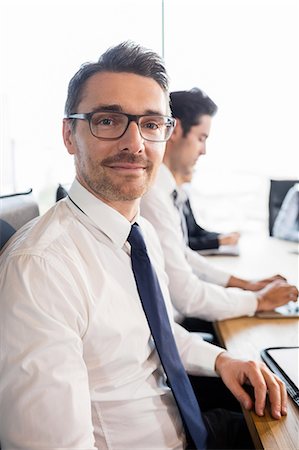 simsearch:6109-08488776,k - Businessman smiling during a meeting at the office Stock Photo - Premium Royalty-Free, Code: 6109-08488793