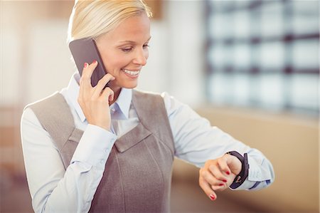 simsearch:6109-08488708,k - Businesswoman using her smartphone and watch at the office Stock Photo - Premium Royalty-Free, Code: 6109-08488712