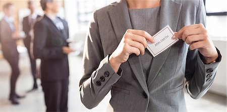 simsearch:6109-08481853,k - Businesswoman putting on name badge at the office Foto de stock - Sin royalties Premium, Código: 6109-08488849